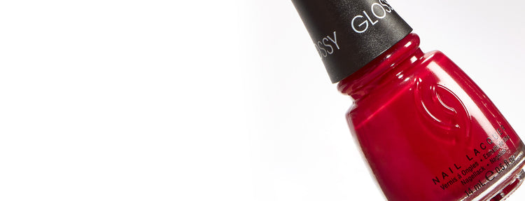 Red nail lacquer bottle with black cap on a white background
