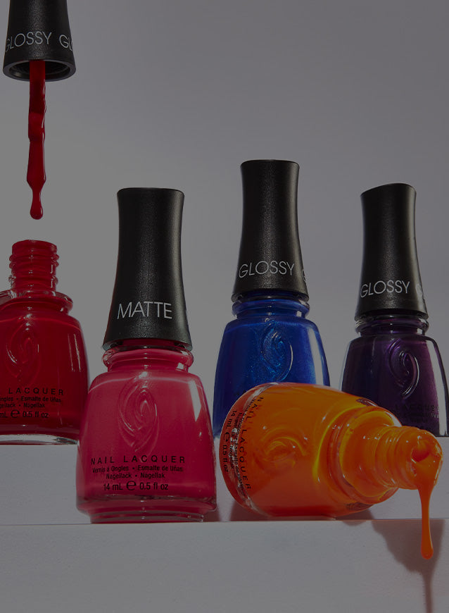 Four bottles of nail lacquers in red, pink, blue, and orange on a white background