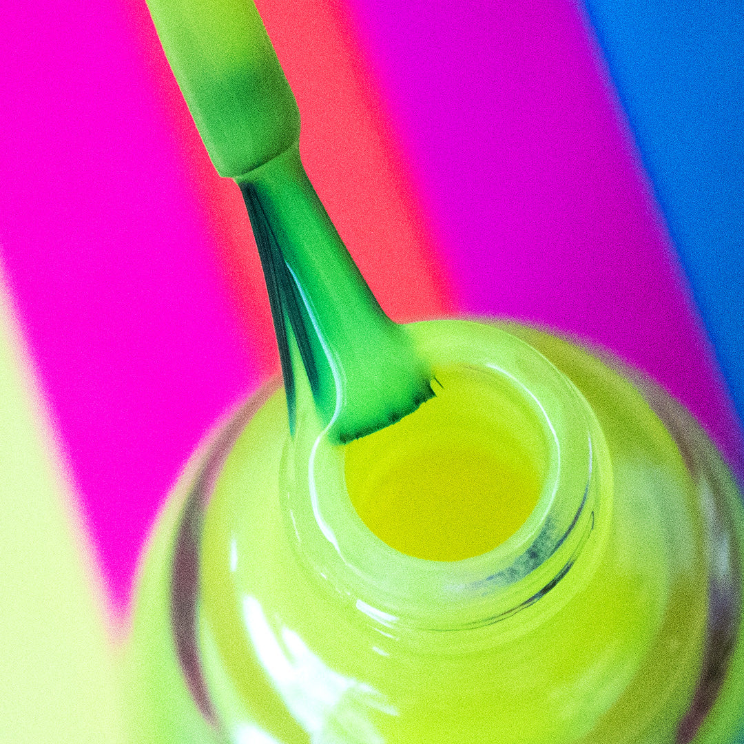 A view of  nail enamel bottle with nail brush on top in a multi-colored background 