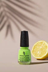 Wide-view of nail color with ripe lemon and a palm leaf shadow as background
